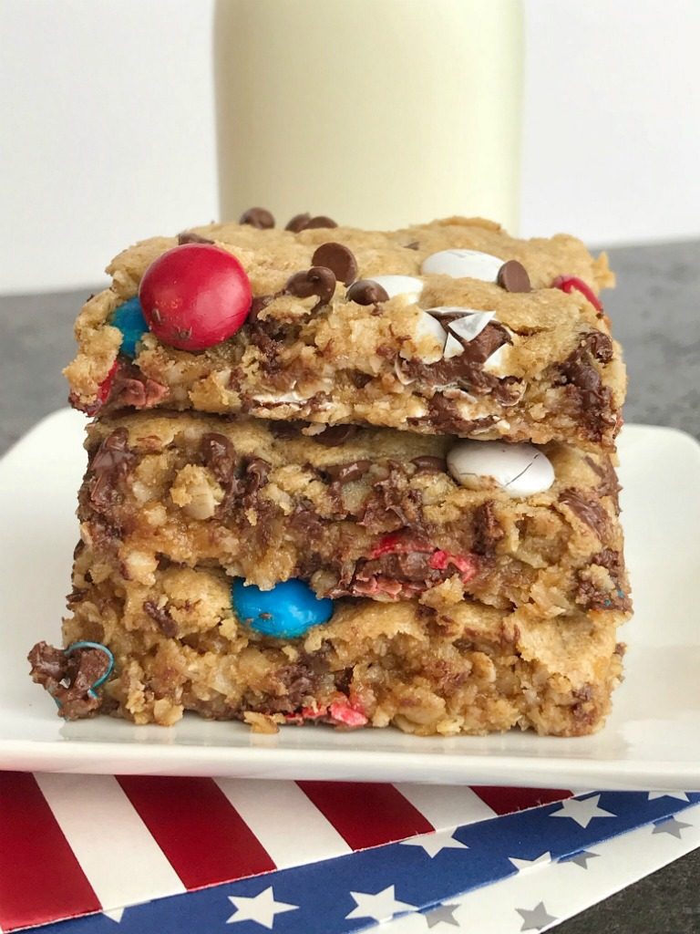 No Flour Red, White, & Blue Cookie Bars | No Flour Desserts | Gluten Free | Cookie Bars | Monster Cookies | Celebrate Memorial Day and 4of of July with these fun and festive no flour red, white, & blue cookie bars. Cookie bars with no flour and loaded with peanut butter, oats, chocolate chips, and m&m's. This holiday dessert recipe will be the hit of the BBQ. Makes an entire cookie sheet so there is plenty to serve a crowd. #glutenfree #4thofjuly #patriotic #easydessertrecipes