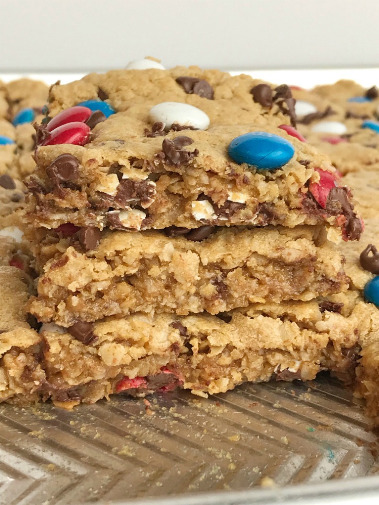 No Flour Red, White, & Blue Cookie Bars | No Flour Desserts | Gluten Free | Cookie Bars | Monster Cookies | Celebrate Memorial Day and 4of of July with these fun and festive no flour red, white, & blue cookie bars. Cookie bars with no flour and loaded with peanut butter, oats, chocolate chips, and m&m's. This holiday dessert recipe will be the hit of the BBQ. Makes an entire cookie sheet so there is plenty to serve a crowd. #glutenfree #4thofjuly #patriotic #easydessertrecipes