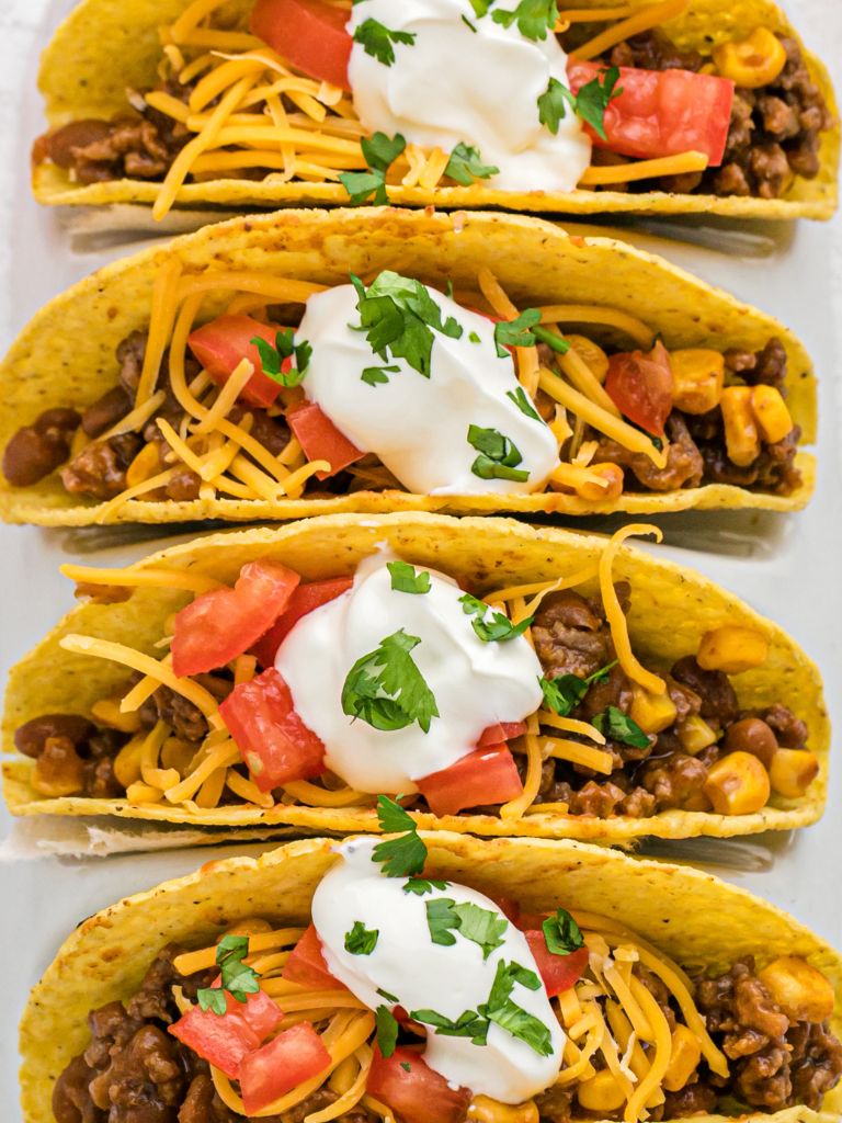 Overhead picture of tacos with toppings against a white background.