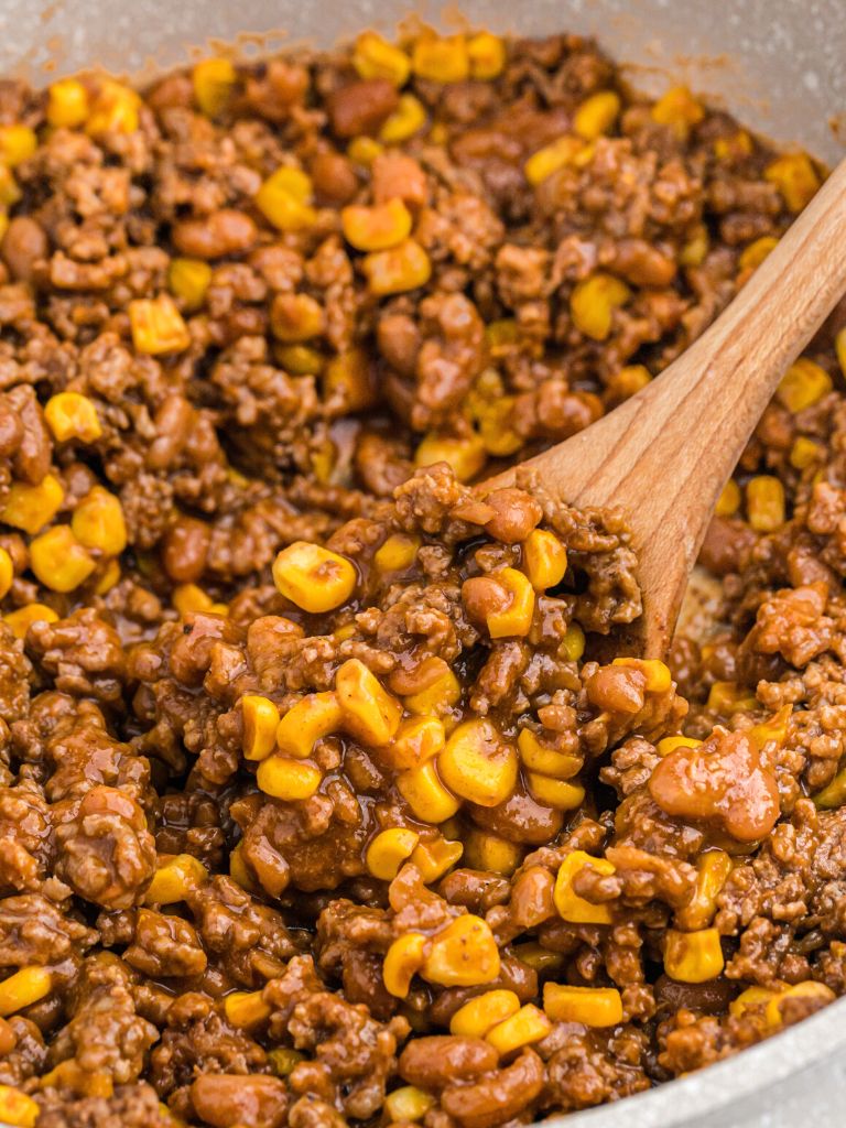 A skillet pan of taco meat with a wooden spoon inside the pan.