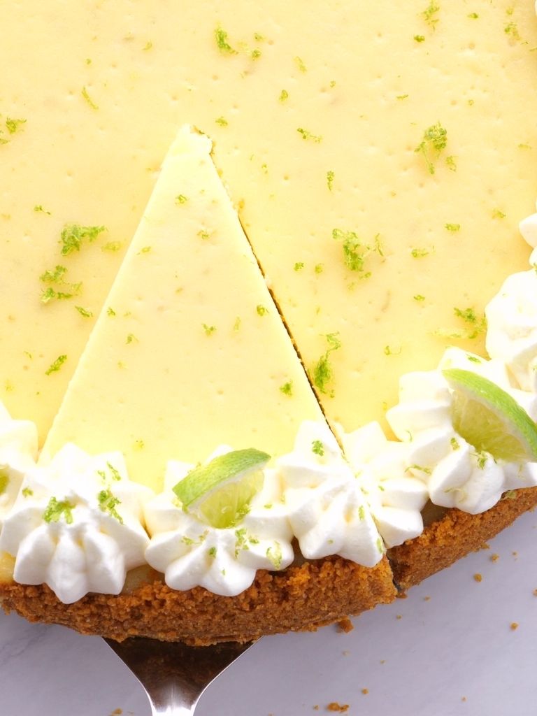 An overhead shot of key lime cheesecake with whipped cream garnish. 