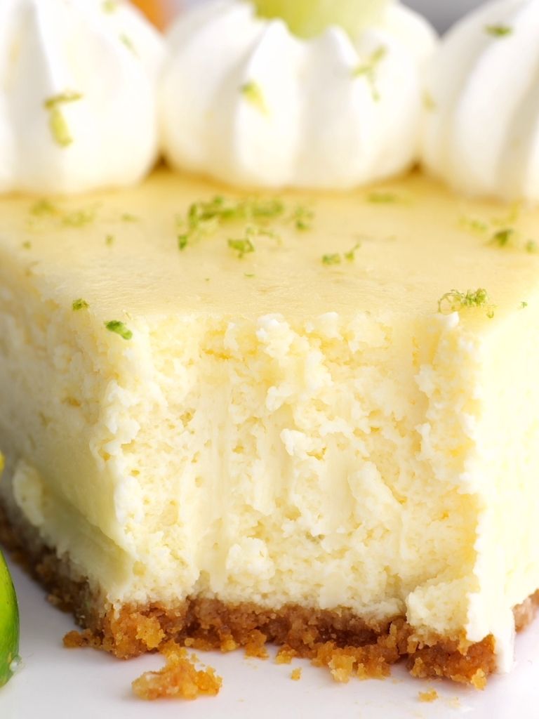 A close picture of a cheesecake with a bite taken out the front to show the texture of the creamy cheesecake. 