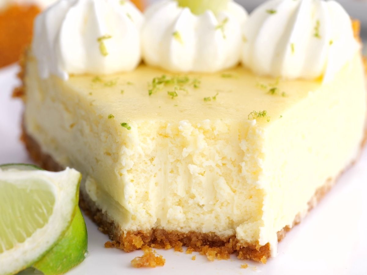 Horizontal photo of key lime cheesecake with a lime wedge next to it. 