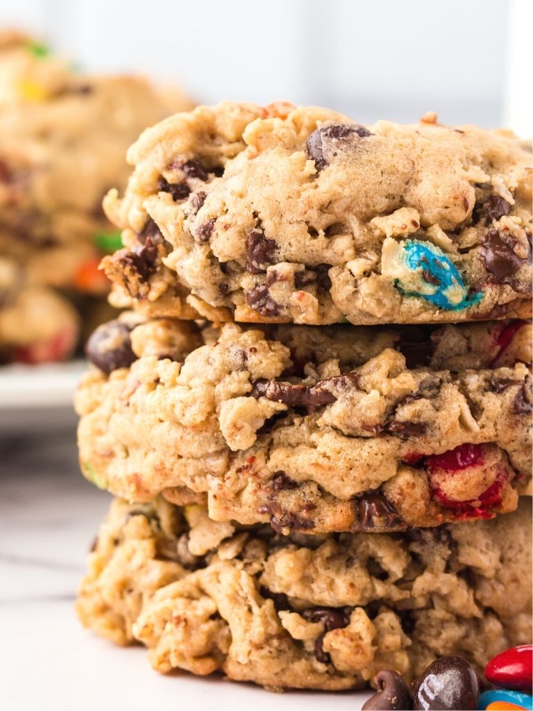Stack of monster cookies with cookies in the background.