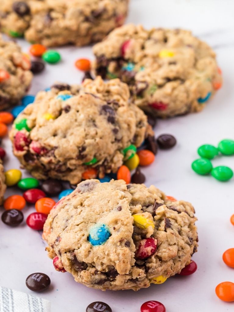 Monster cookies on a marble background, close up shot of one cookie, with m&m's beside it. 