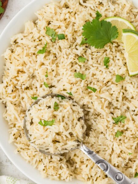 Top view of a bowl of rice with cilantro and a spoon in it.