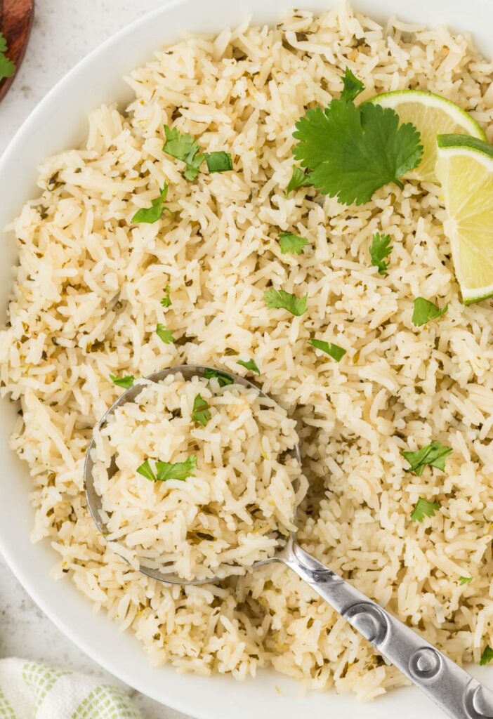 Top view of a bowl of rice with cilantro and a spoon in it.