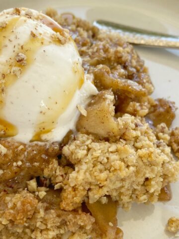 Apple Crumble with a delicious buttery oatmeal cookie crumble. Tart apples in cinnamon & sugar and butter topped with an easy oatmeal cookie mix crumble topping. As it bakes it creates this buttery brown sugar syrup! Serve with vanilla ice cream for the best apple crumble dessert ever.