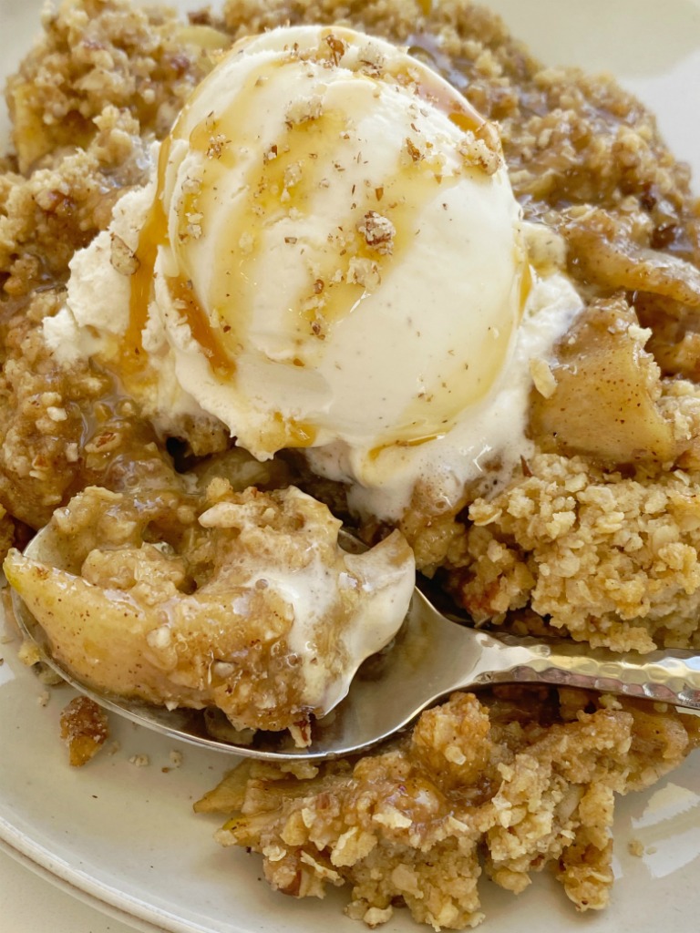 Apple Crumble with a delicious buttery oatmeal cookie crumble. Tart apples in cinnamon & sugar and butter topped with an easy oatmeal cookie mix crumble topping. As it bakes it creates this buttery brown sugar syrup! Serve with vanilla ice cream for the best apple crumble dessert ever.