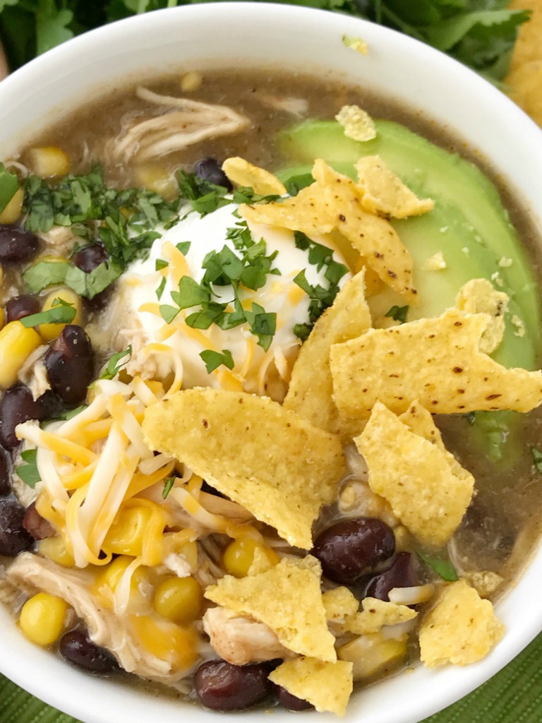Chicken Enchilada Soup | Soup Recipe | Chicken Recipe | Chicken enchilada soup made in the slow cooker. Loaded with chicken, black beans, corn, that simmers in a green chili enchilada sauce and chicken broth in the crock pot. Serve with avocado, sour cream, cheese, and chips! 