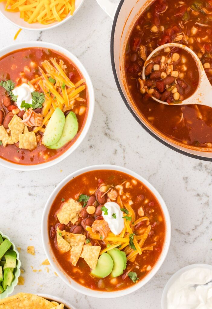 Top view of the pot of chicken chili with serving bowls of it.