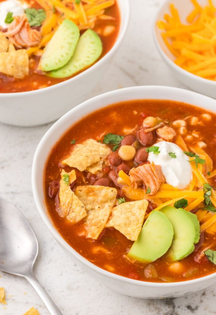 Bowl of chicken chili with a spoon next to it.