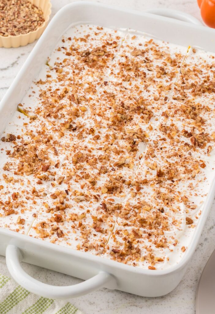The pan of pumpkin dessert ready to serve with chopped pecans on top. 