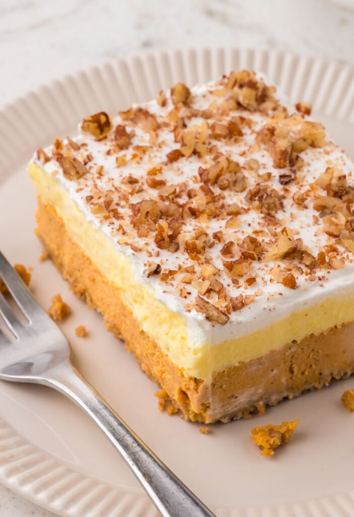 Slice of the layered pumpkin dessert on a plate with a fork