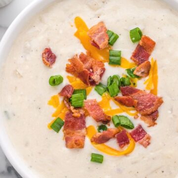 Close up picture of a bowl of potato soup topped with bacon and cheese.