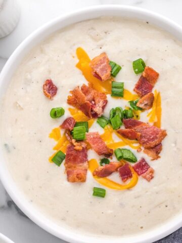 Close up picture of a bowl of potato soup topped with bacon and cheese.