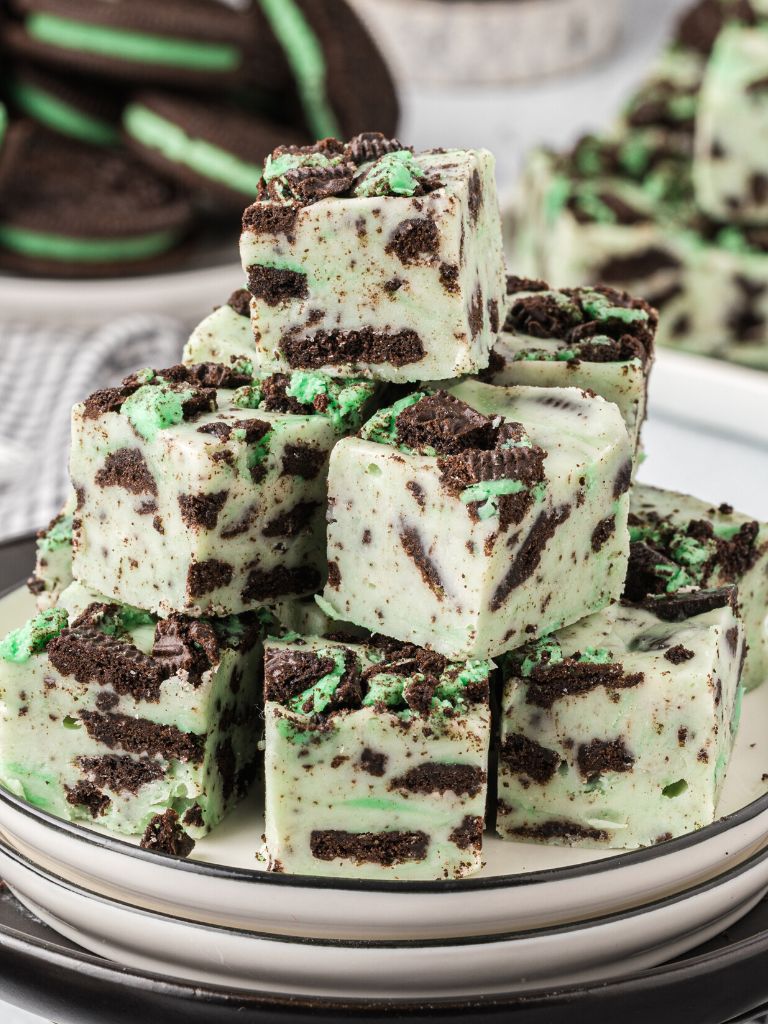 A plate of stacked fudge with mint oreo cookies in the background. 