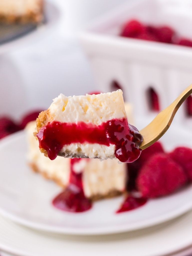 A fork with a bite of cheesecake on it up close.
