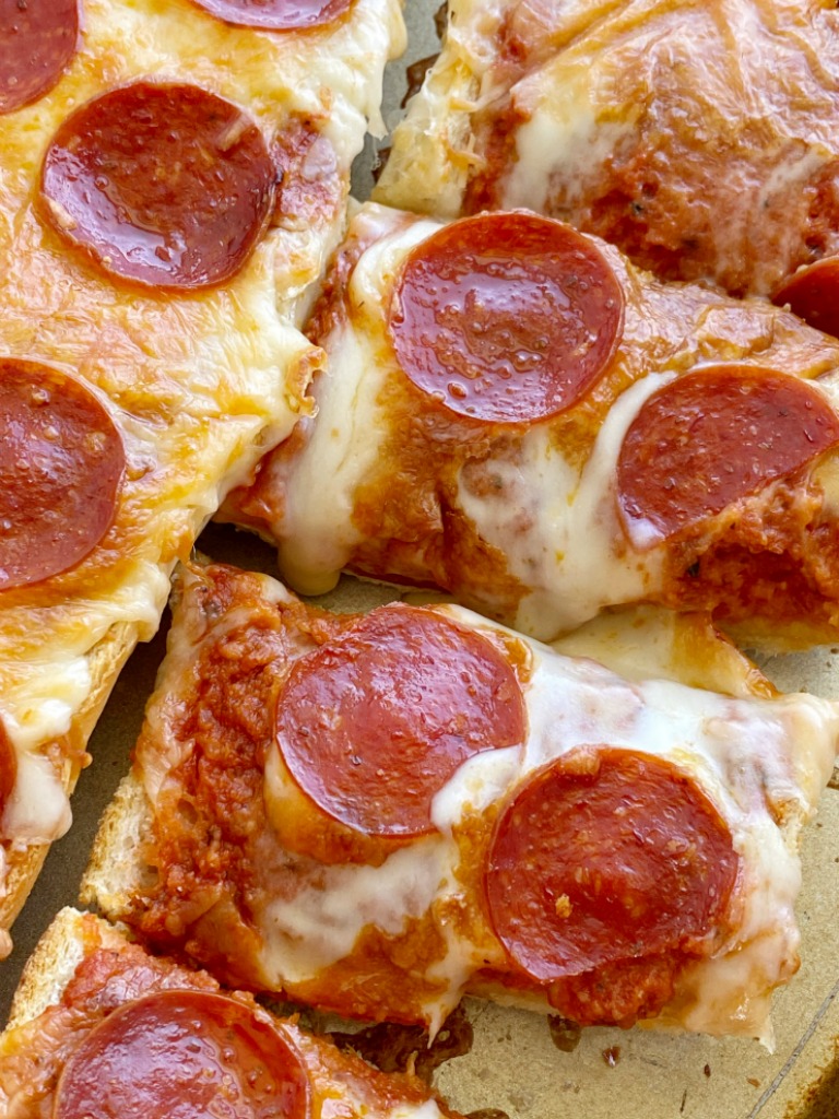 French Bread Pizza is perfectly crispy on the outside. No soggy pizza here! Topped with a jar of pizza sauce with added seasonings, pepperoni, and lots of cheese. It's a 30 minute dinner that's perfect for a busy weeknight meal.