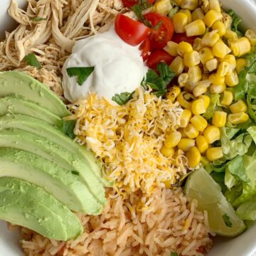 Lime Chicken Taco Bowls | Taco Bowls | Crockpot Recipe | Taco Bowls loaded with perfectly shredded and seasoned lime chicken that's made in the crock pot! Serve with rice, corn, lettuce, cheese, avocado, and salsa for a delicious, make it yourself dinner. #mexicanfoodrecipes #mexicanfood #dinnerideas #tacobowls #crockpotrecipes #slowcooker