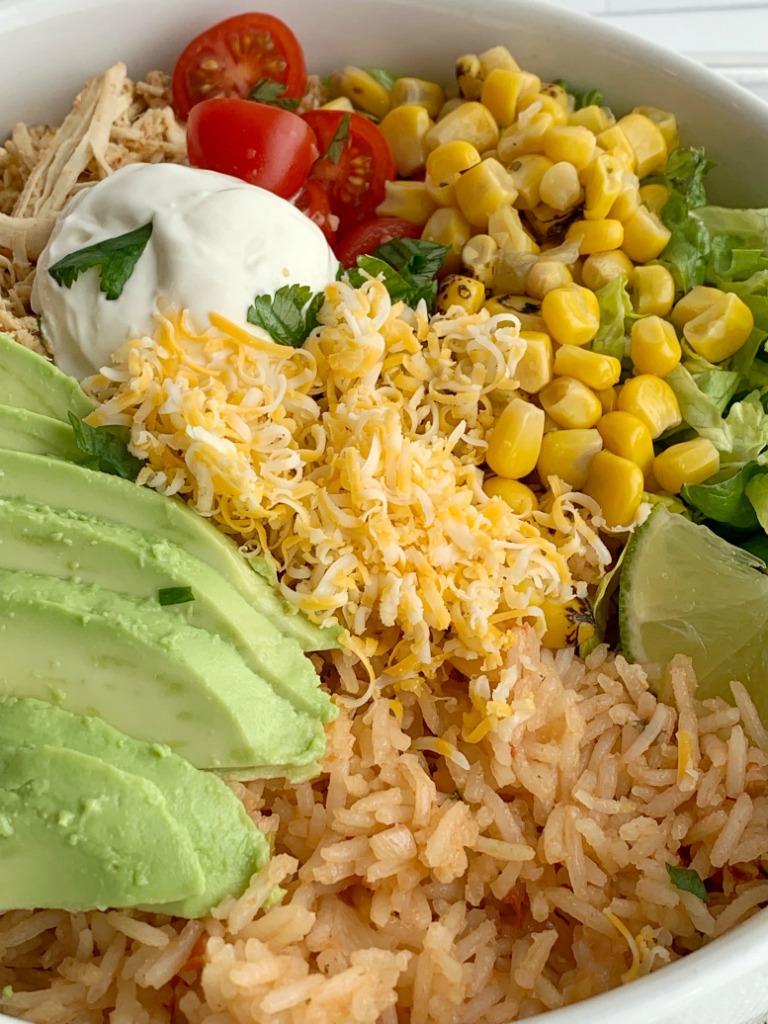Lime Chicken Taco Bowls | Taco Bowls | Crockpot Recipe | Taco Bowls loaded with perfectly shredded and seasoned lime chicken that's made in the crock pot! Serve with rice, corn, lettuce, cheese, avocado, and salsa for a delicious, make it yourself dinner. #mexicanfoodrecipes #mexicanfood #dinnerideas #tacobowls #crockpotrecipes #slowcooker