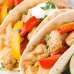 three fajitas on a plate inside a flour tortilla.