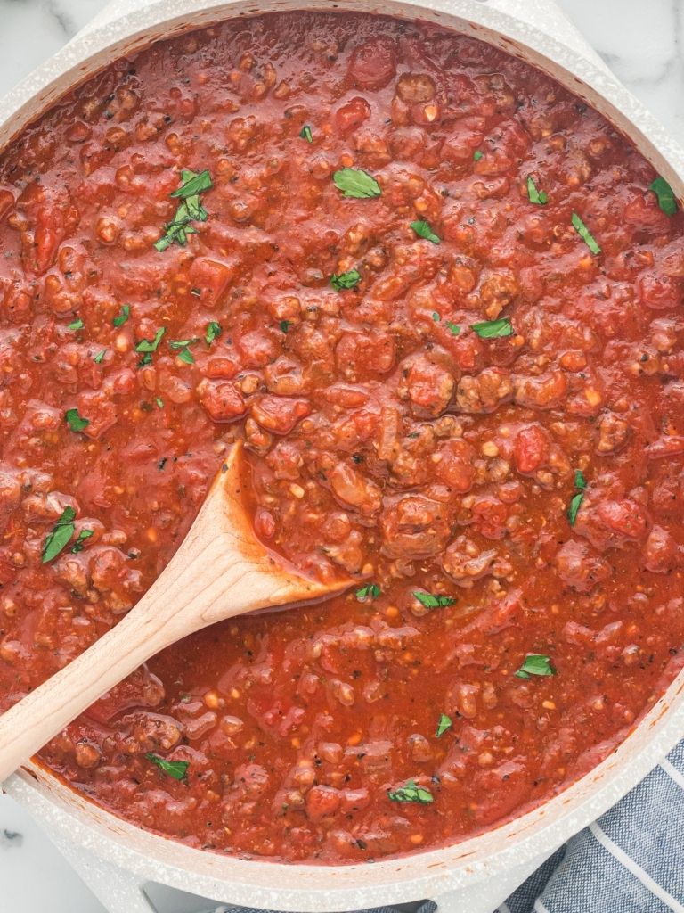 Overhead shot of spaghetti meat sauce with a wooden spoon inside the pan. 