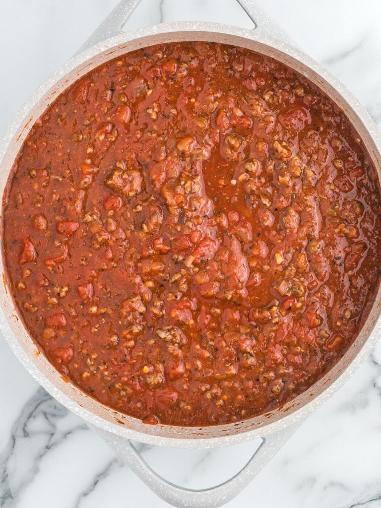 A pan of spaghetti meat sauce on a marble countertop. 