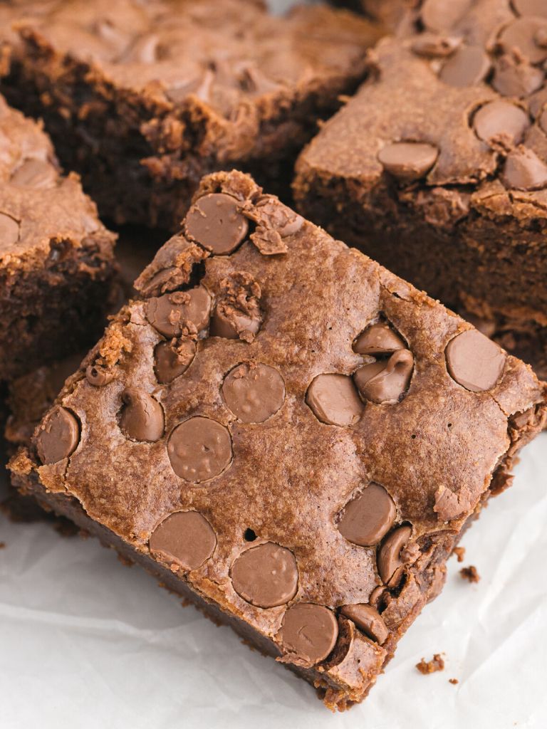 One brownie square leaning up on another stack of brownies with chocolate chips on top of it. 