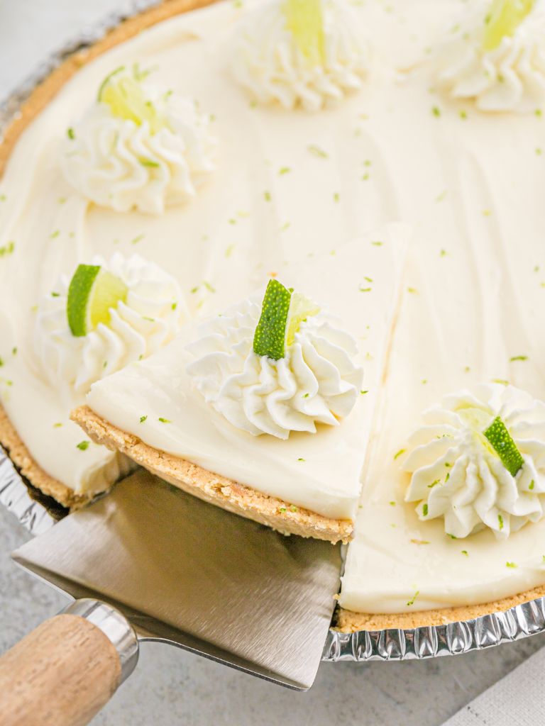 A pie tin with key lime pie inside of it with pie serving spoon