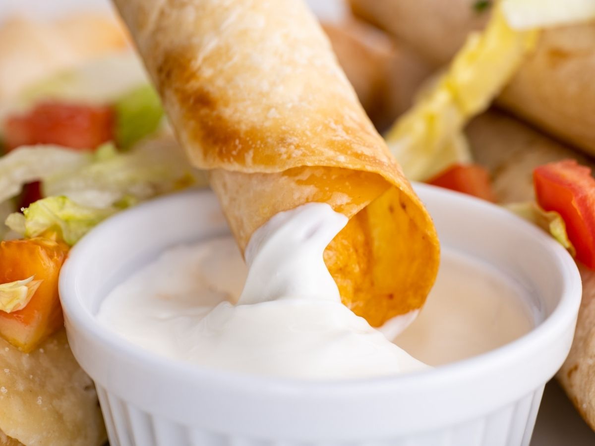 A flauta being dipped into some sour cream.