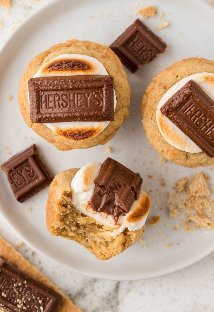 A hero image of a plate of smores cookie cups with one turned sideways to show the middle. 