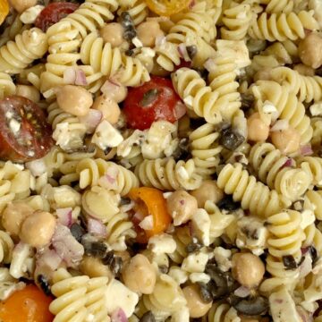 Greek Pasta Salad | Pasta Salad Recipes | Easy Greek Pasta Salad with tender spiral pasta, feta cheese, black olives, cherry tomatoes, red onion, and chickpeas with a easy dressing of Greek Vinaigrette salad dressing. So much flavor and texture, it's sure to be a hit. #salad #pastasalads #greek #sidedish #summerrecipes #pastasaladrecipes #recipeoftheday