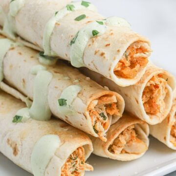 Stack of taquitos with sauce and chopped cilantro.