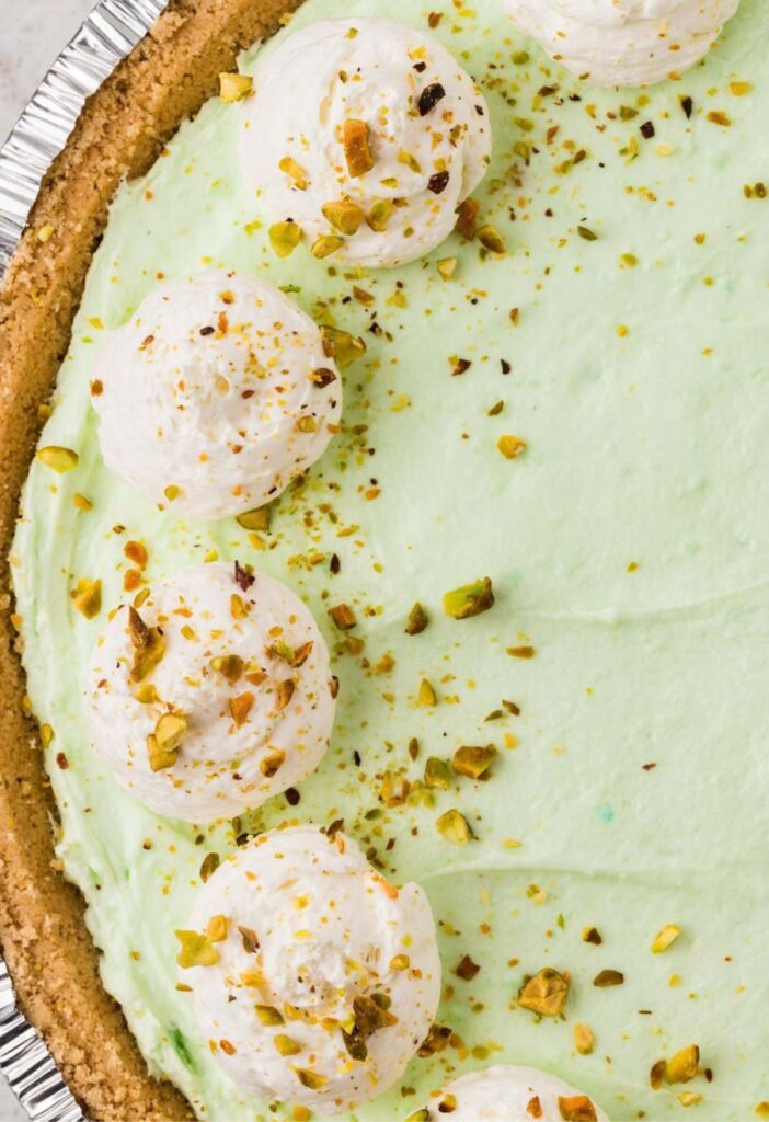A pistachio pie with whipped cream and pistachios.
