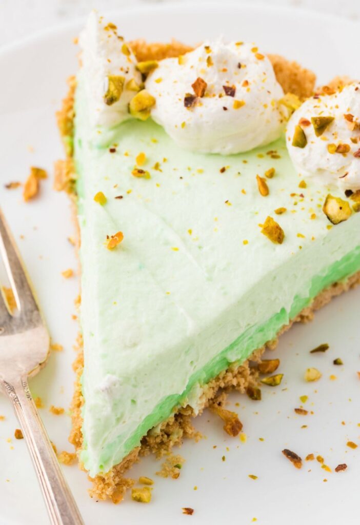 A slice of the no bake pistachio cheesecake pie with a fork on a plate.