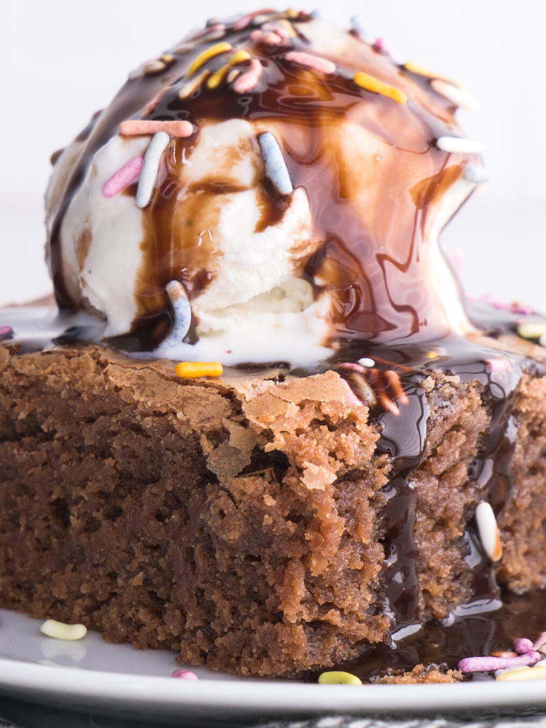 Homemade brownies with a scoop of vanilla ice cream, hot fudge, and sprinkles.