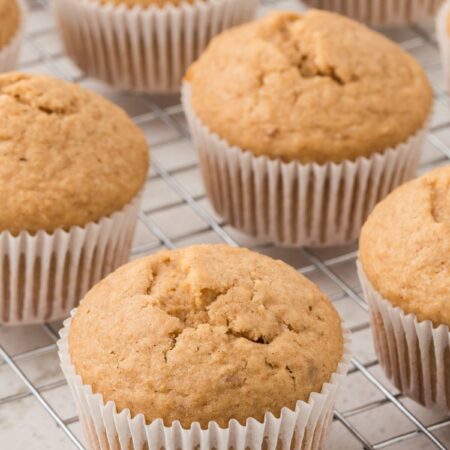 Cooling rack with the muffins inside wrappers on it.