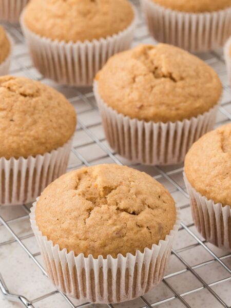 Cooling rack with the muffins inside wrappers on it.