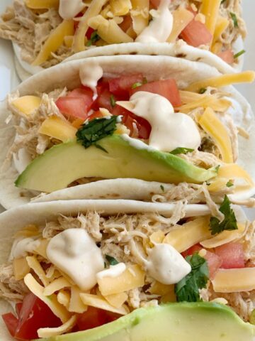 Slow Cooker Chicken Queso Tacos | Tacos | Chicken Tacos | Chicken Tacos made in the slow cooker with only 4 ingredients! Shredded chicken with queso, inside a flour tortillas with all the toppings you love. These queso chicken tacos are so easy and full of creamy queso flavor. #tacorecipes #tacos #dinner #dinnerrecipes #chicken #chickenrecipes #recipeoftheday