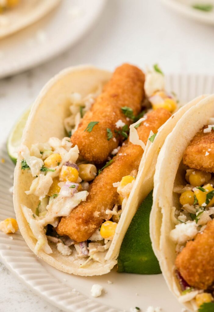 Fish tacos in corn tortillas with a lime wedge