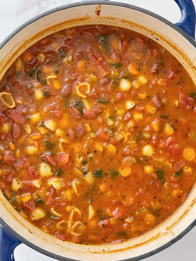 A pot with minestrone soup that has been simmer on the stove top. 