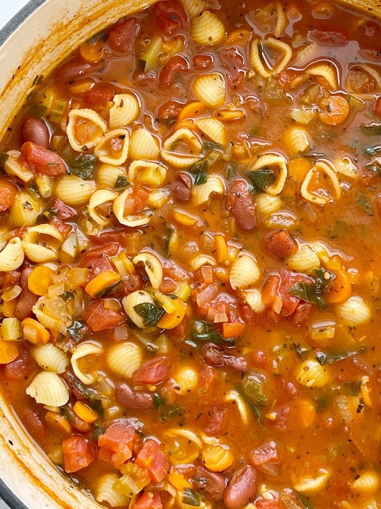 Pot of minestrone soup with pasta, beans, vegetables in a tomato sauce vegetable broth base.