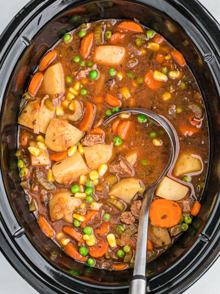 A crock pot with stew inside of it and a silver label with some in it. 