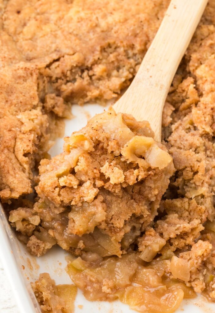 Pan of apple cobbler with a wooden serving spoon in it