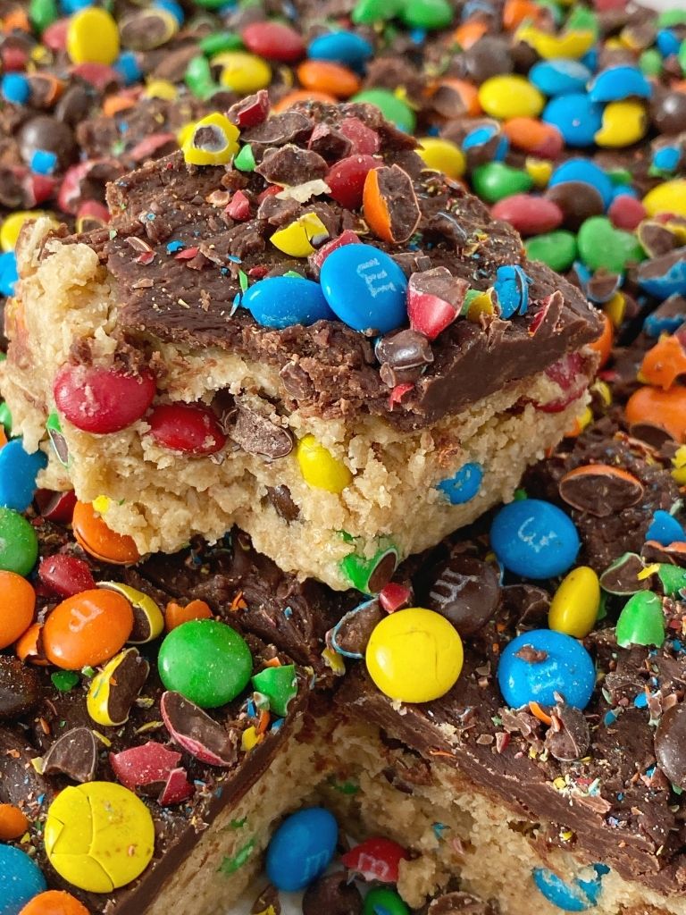 Monster Cookie Dough Bars are no bake and egg free! Monster cookie dough with peanut butter, quick oats, and mini m&m's topped with milk chocolate ganache. 