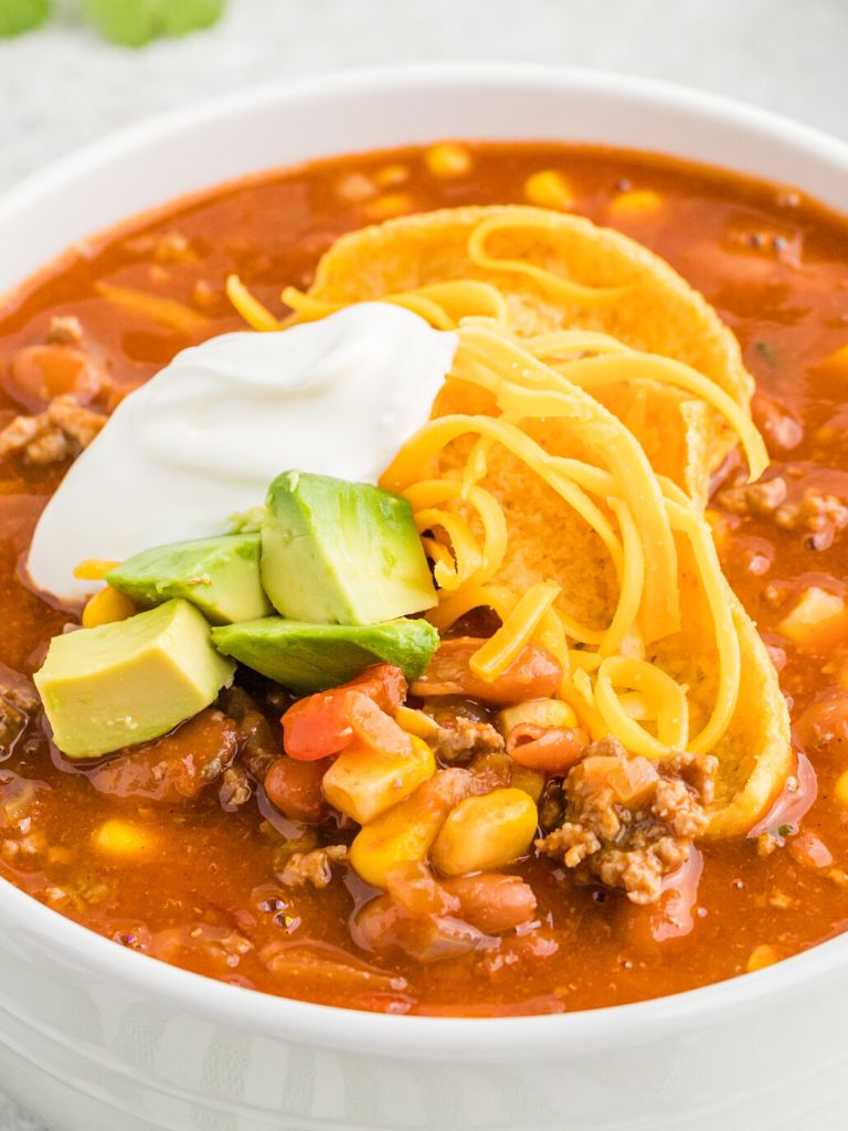 Bowl of taco soup with toppings on it.