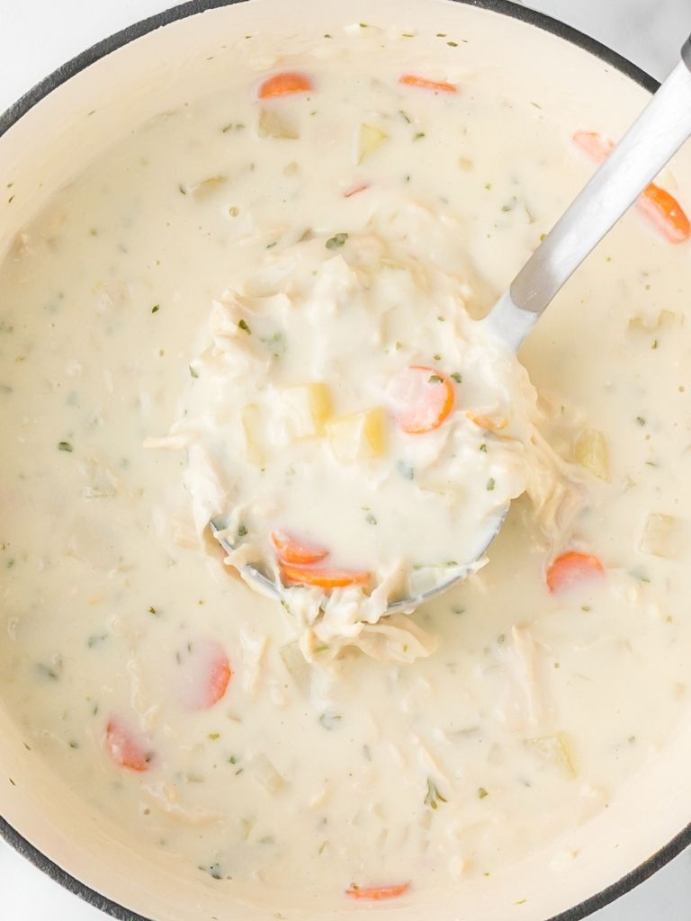 Pot of soup with a soup ladle inside of it. 