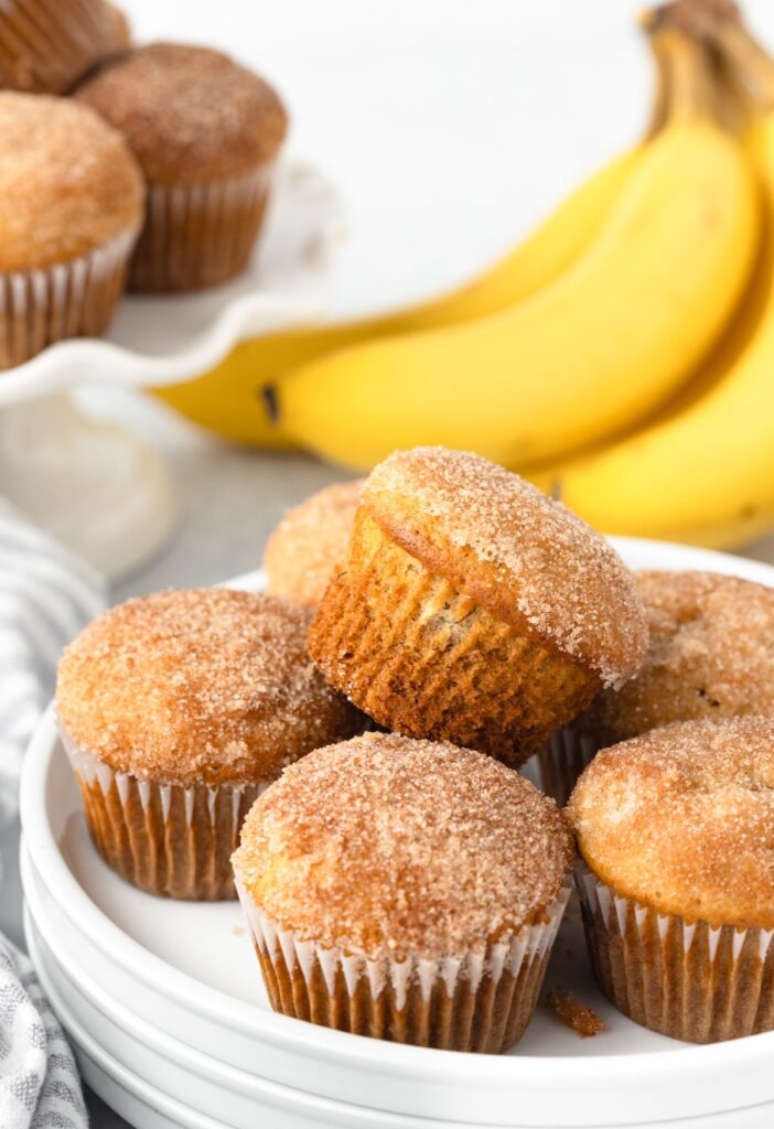 A plate of muffins with bananas in the background