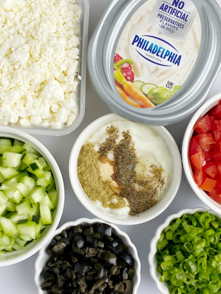 Greek Dip Recipe | Dip Recipe | Party Dips | Appetizer Recipe | This Greek inspired party dip is the best Dip Recipe you will make! Layers of cream cheese, yogurt, spices, tomatoes, cucumbers, olives, and feta cheese. Serve with crackers and pita bread for an amazing appetizer. #diprecipes #appetizers #superbowlrecipes #greekdip #recipeoftheday